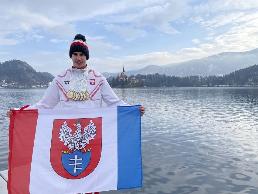 Michał Perl z flagą Legionowa na tle jeziora